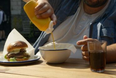 Hombre comiendo hamburguesa con mostaza