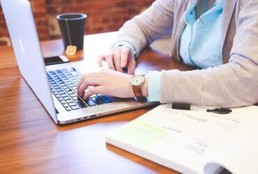 Mujer trabajando con portatil y apuntes