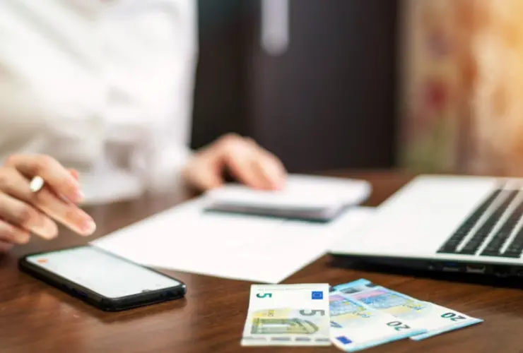 Mujer-haciendo-cuentas-con-portatil_-dinero-y-movil