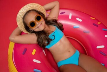 Niña en bikini y gorro tumbada en flotador