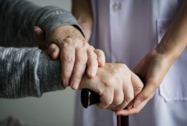 Persona mayor con ayuda para sujetar bastón