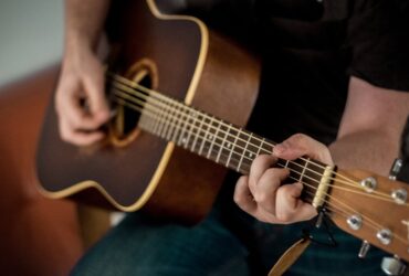 Persona aprendiendo a tocar guitarra acústica