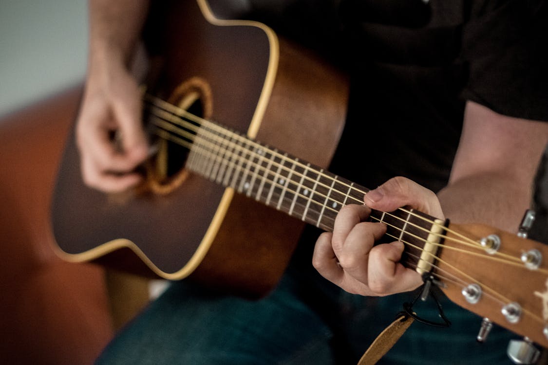 Persona aprendiendo a tocar guitarra acústica